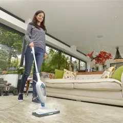 Kobieta sprząta salon mopem parowym.