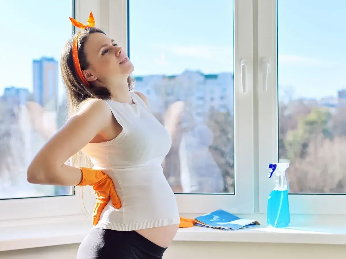 Kobieta w ciąży myjąca okna z ostrożnością